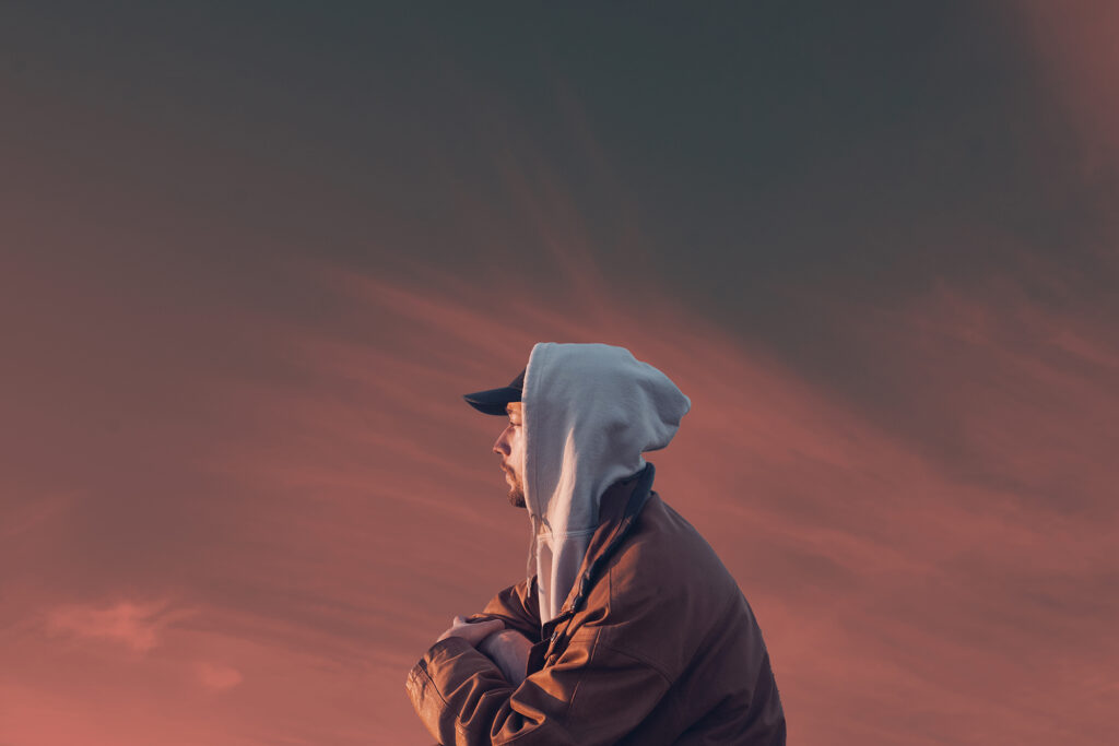 Ein junger Mann im Profil mit Baseballkappe und Hoodie